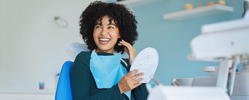 img-bioceramic-root-canal-sealers Woman holding dental mirror in modern dental office, smiling at camera