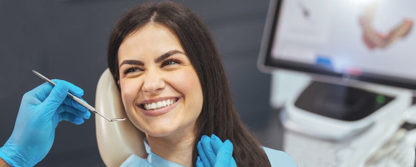 Dental professional in blue gloves smiling at patient during examination in modern dental clinic.