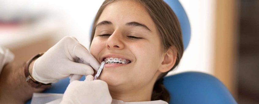 Female patient receiving dental examination from dentist in clinical chair at dental studio.