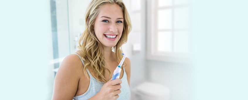 img-rotadent Smiling woman in dental office giving thumbs up approval gesture