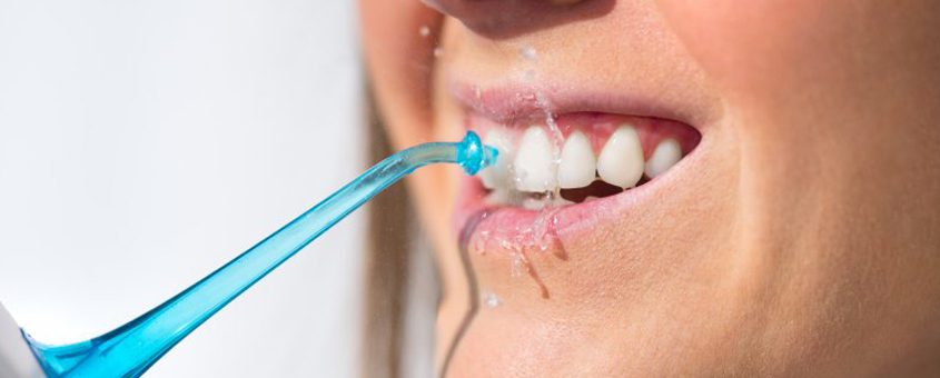 img-waterpik Person brushing teeth with blue toothbrush against white background, demonstrating proper dental hygiene.