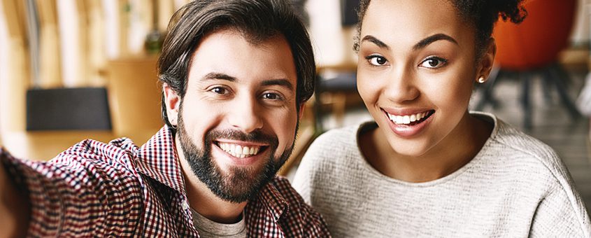 Two smiling people posing together in a warm, welcoming dental office setting.