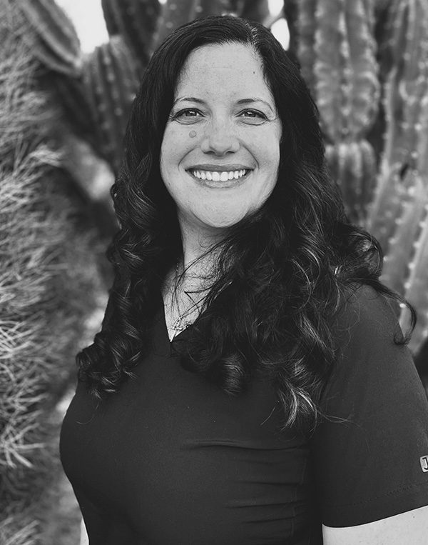 Black and white portrait of smiling woman with long dark hair against textured background