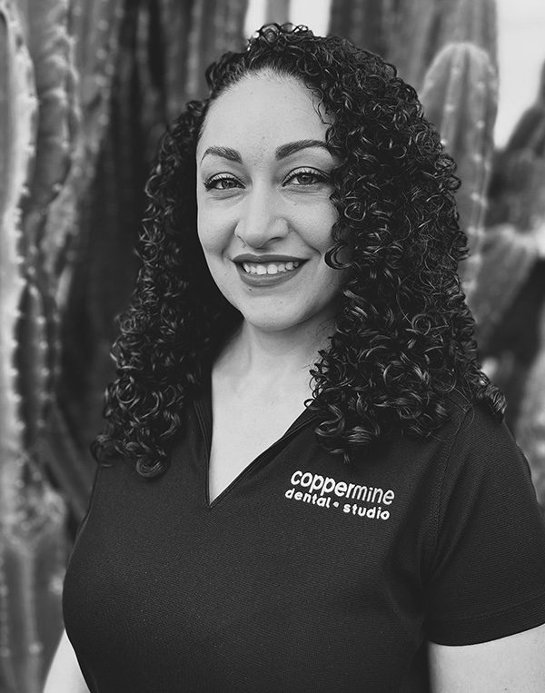 Professional headshot of smiling woman wearing CopperMine Dental Studio uniform in dental office setting.