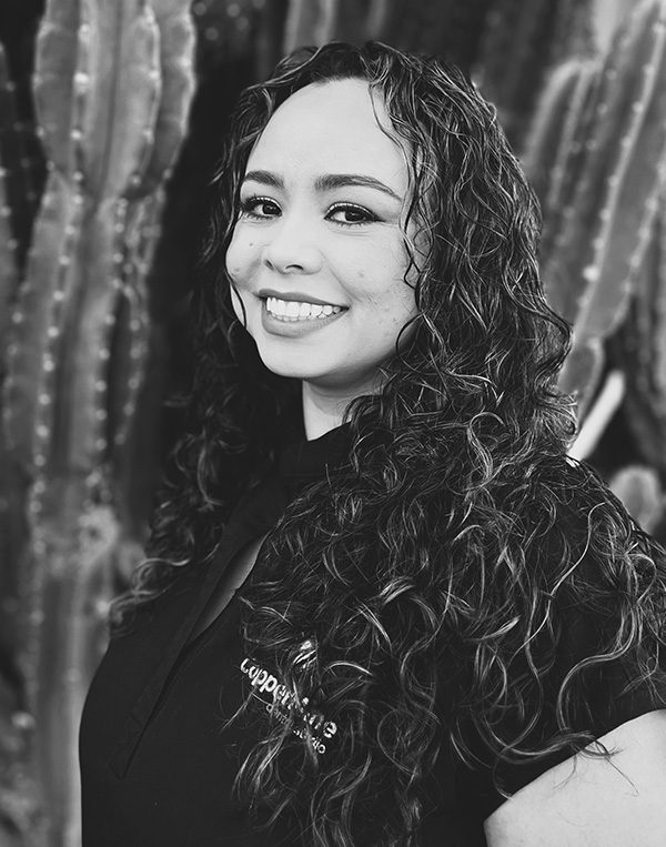 Woman smiling at camera in professional black and white portrait photo at dental studio.