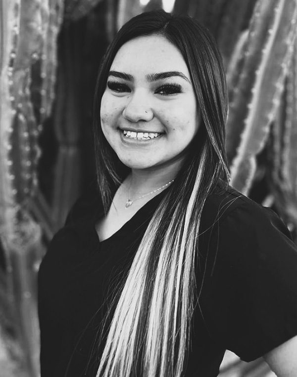 Smiling woman in black blazer and striped scarf, professional black and white portrait photo.