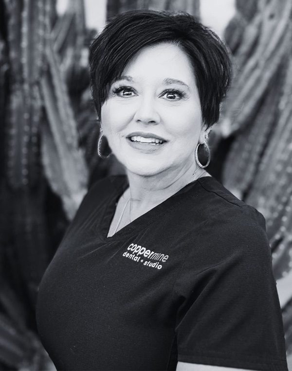 Professional headshot of woman smiling at CopperMine Dental Studio, wearing dark uniform.