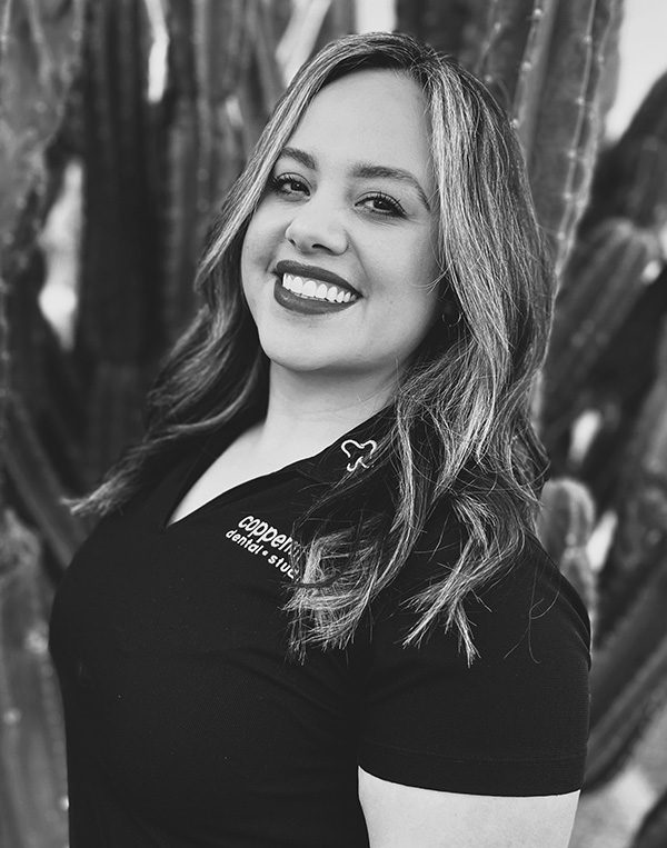 Professional headshot of smiling woman with long hair against textured background for dental studio.