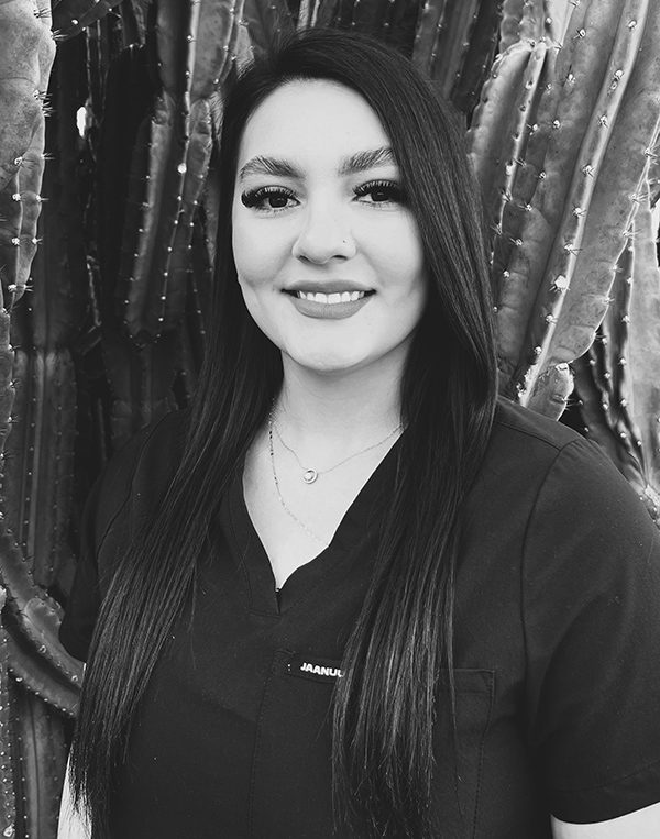 Professional headshot of woman with long dark hair smiling at dental studio.