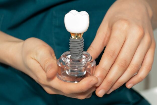 Close-up of a person holding a dental implant model.