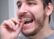 A man placing an Invisalign aligner onto his teeth.