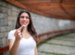 Smiling woman holding a clear retainer after Invisalign treatment to maintain teeth alignment and long-term results.