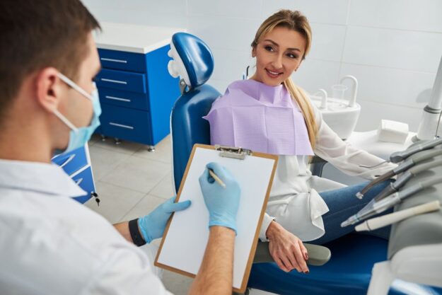 Family dentist reviewing and updating a patient’s dental history during a routine checkup in a modern dental office.