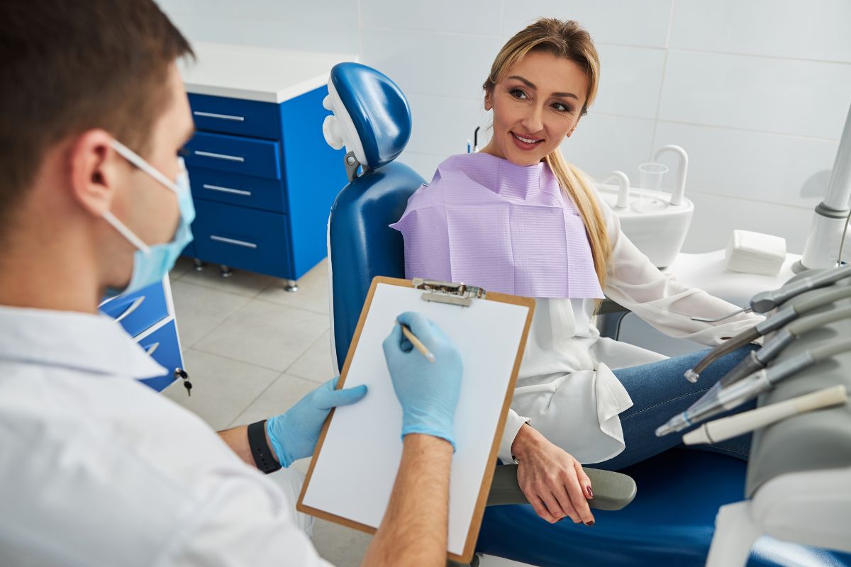 Family dentist reviewing and updating a patient’s dental history during a routine checkup in a modern dental office.