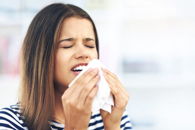 Woman experiencing seasonal allergies that may impact oral health and dental comfort.