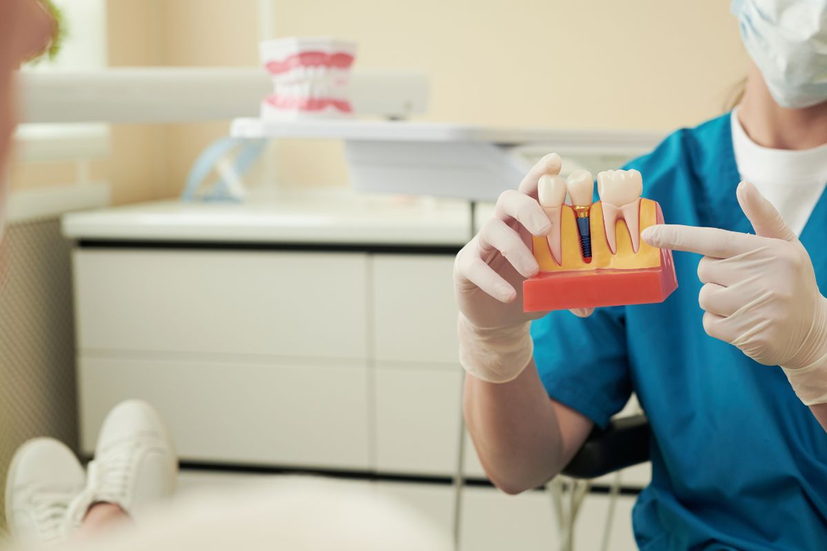 Dental Implants Dentist explaining a dental implant model to a patient during post-surgery recovery consultation.